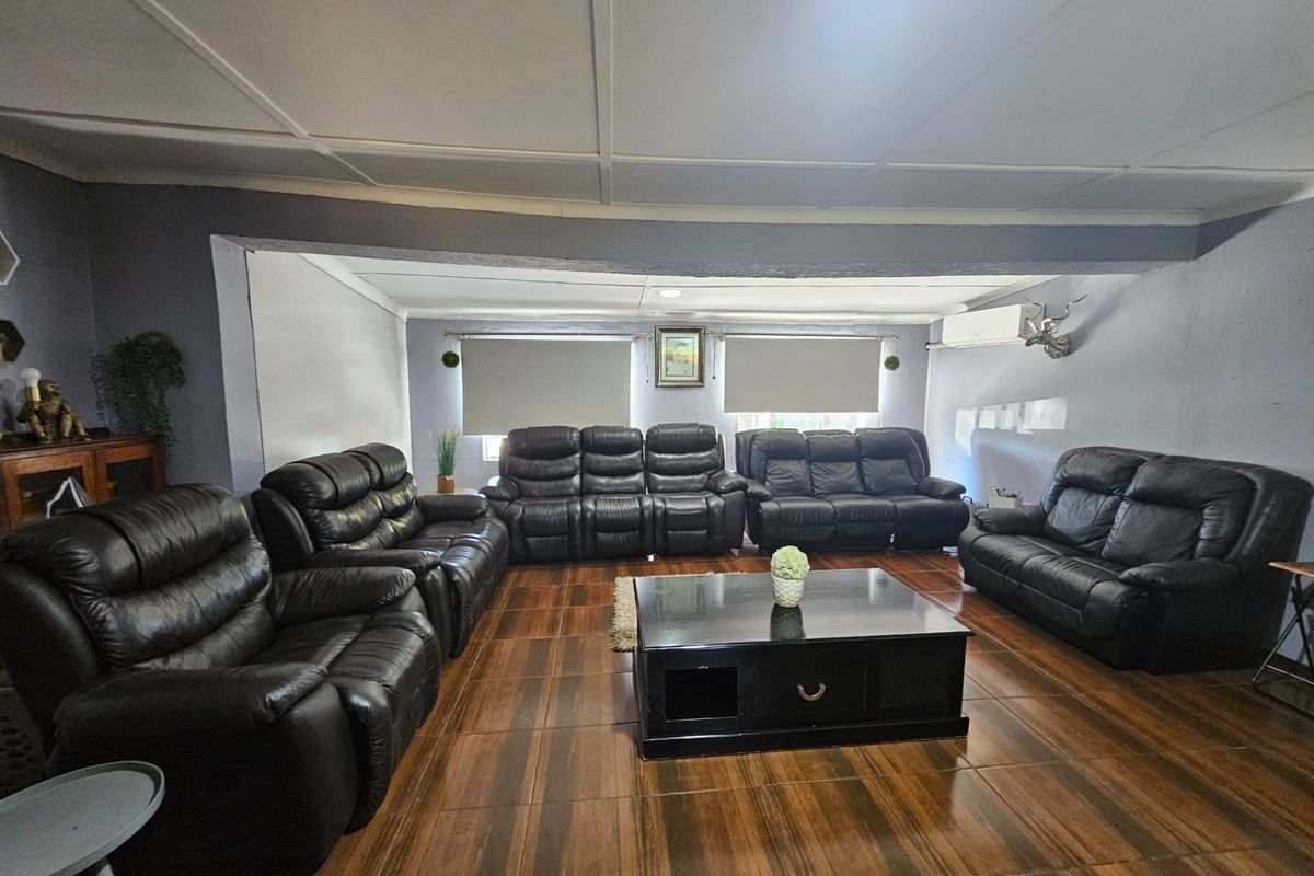 Spacious living room featuring dark tiled flooring, split-system air conditioning, and neutral wall tones, offering a comfortable area for relaxation.