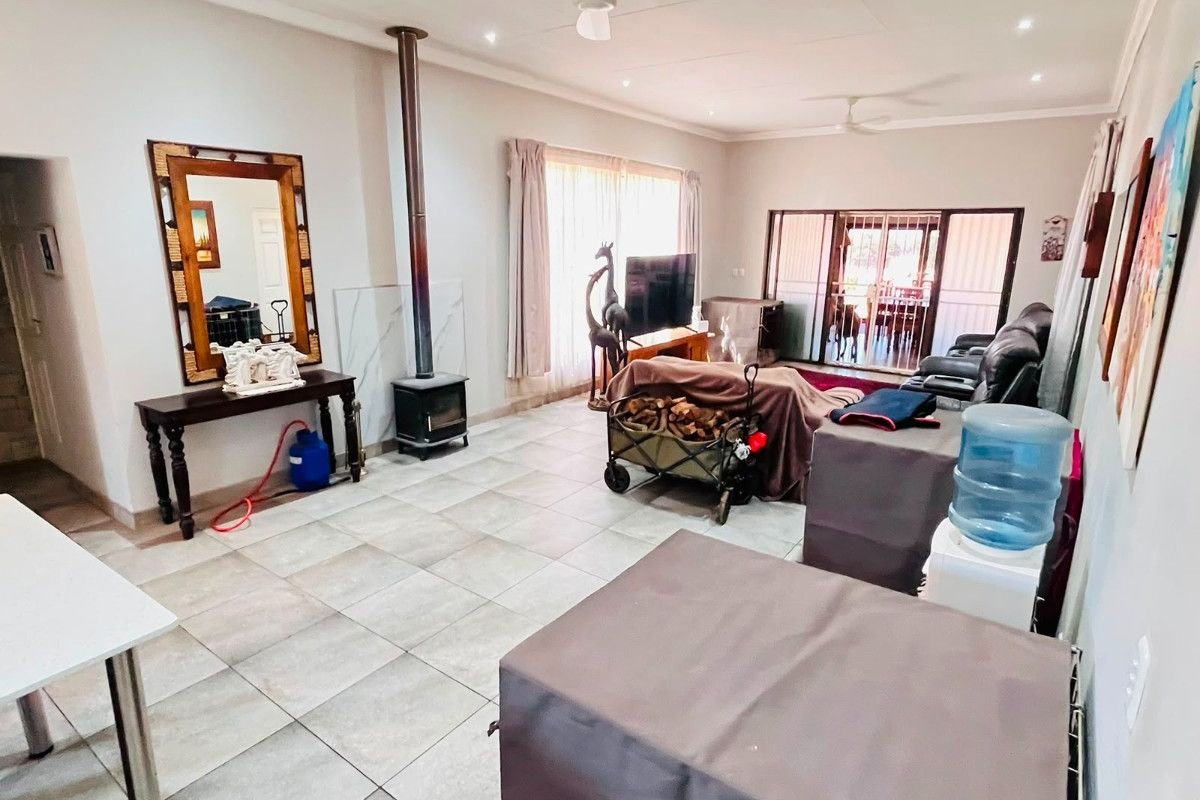 Spacious living room featuring tiled flooring, a freestanding fireplace, ceiling fans, and sliding glass doors leading to an outdoor area.
