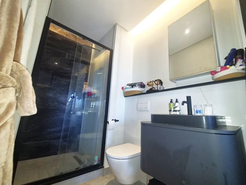 Modern bathroom featuring a walk-in shower with glass enclosure, wall-mounted toilet, and a sleek vanity with a vessel sink.