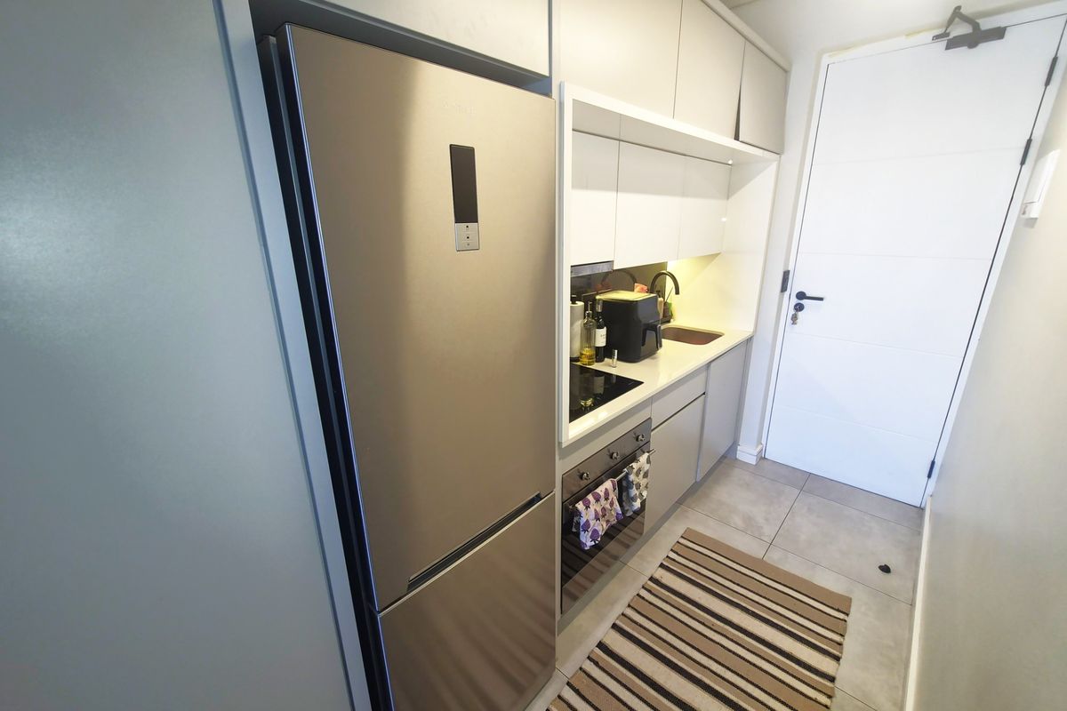 A compact, modern kitchen featuring sleek cabinetry, integrated oven, electric hob, and tiled flooring, providing a functional and efficient cooking space.