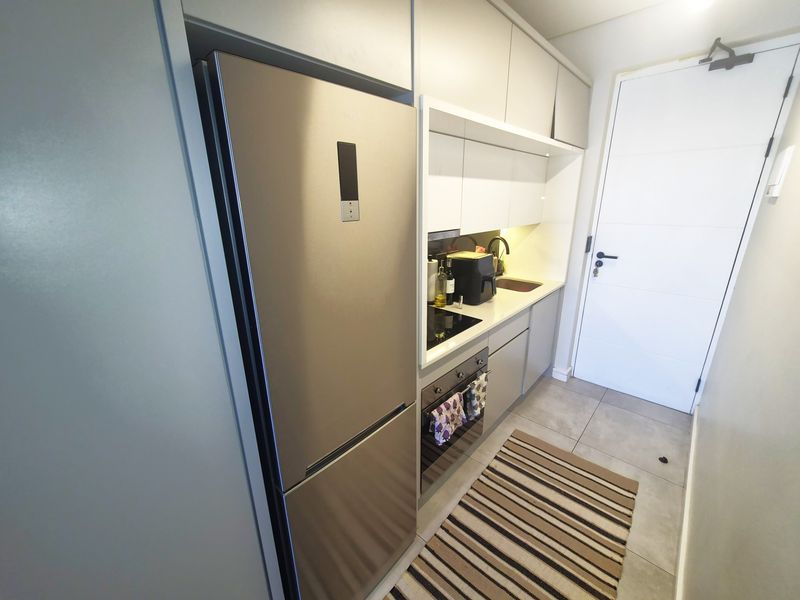 A compact, modern kitchen featuring sleek cabinetry, integrated oven, electric hob, and tiled flooring, providing a functional and efficient cooking space.
