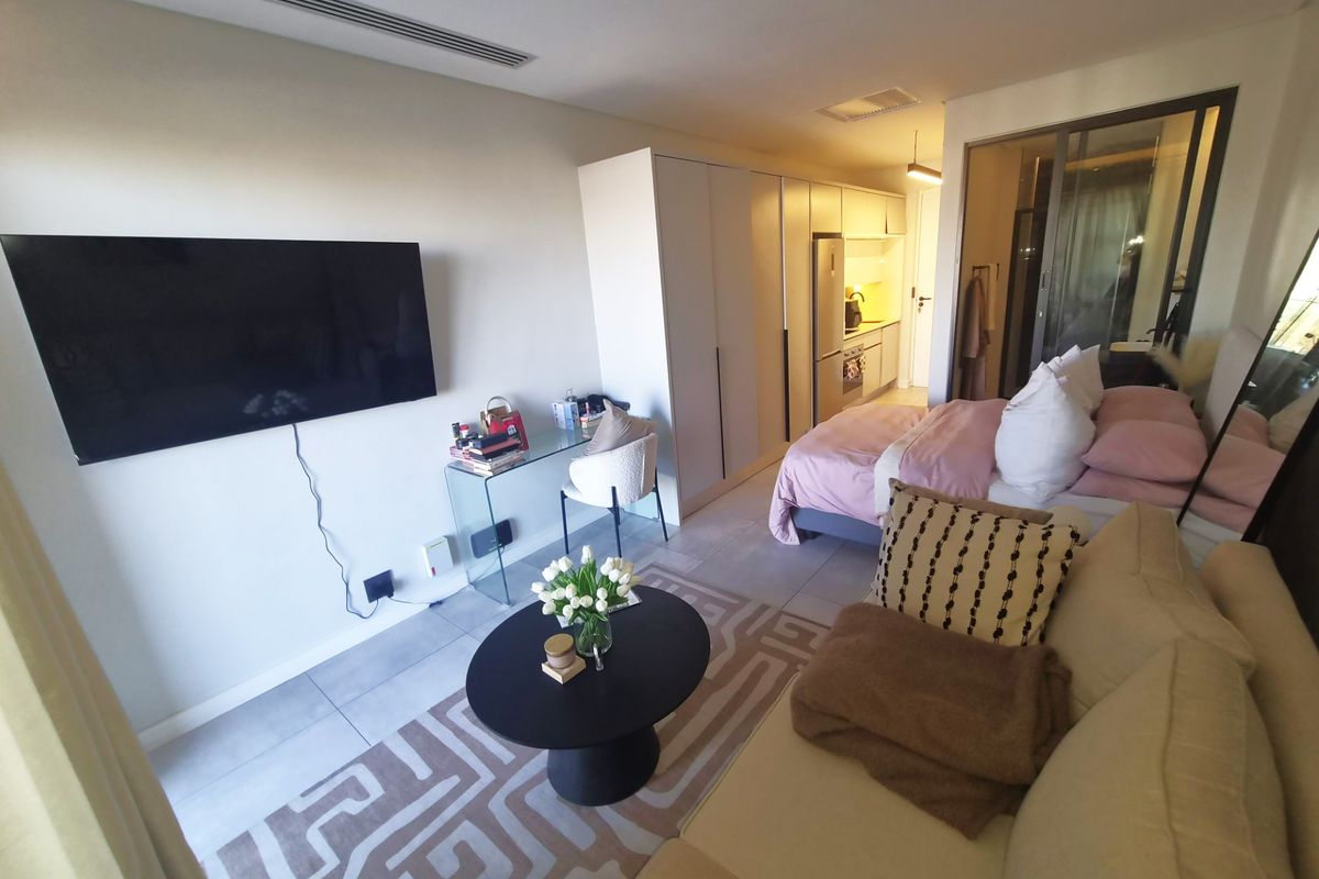 Modern open-plan studio apartment featuring tiled flooring, recessed ceiling lighting, and integrated kitchen cabinetry, creating a functional and cohesive living space.
