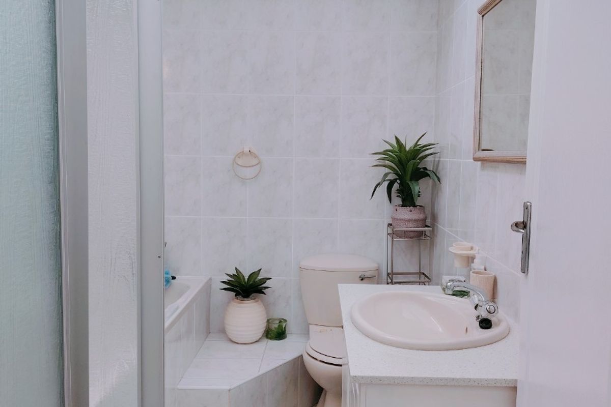 A functional bathroom featuring a vanity with integrated sink, a toilet, and a combined bathtub and shower enclosure with tiled finishes.