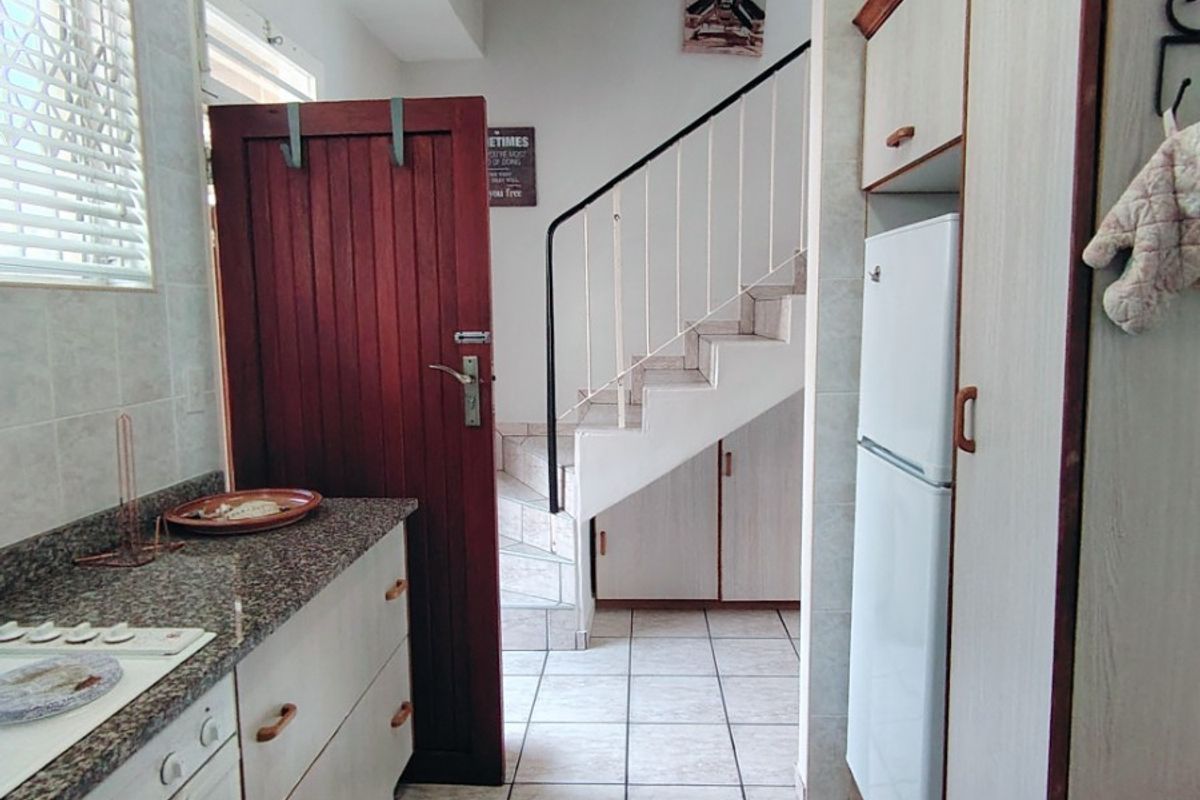 A functional kitchen featuring granite countertops, built-in cabinetry, and a built-in oven, with an adjacent staircase leading to the upper level.