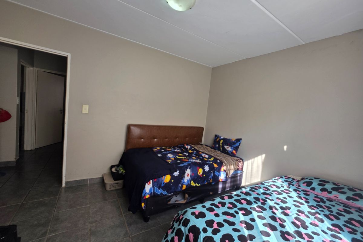 A functional bedroom featuring tiled flooring and neutral wall finishes, providing a simple and practical living space.