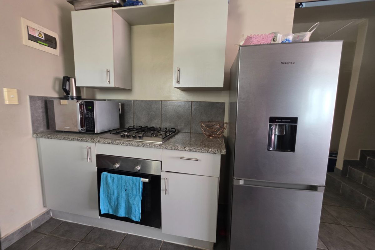 Compact kitchen featuring built-in cabinetry, granite countertops, a gas hob, and a built-in oven with tiled backsplash and flooring.