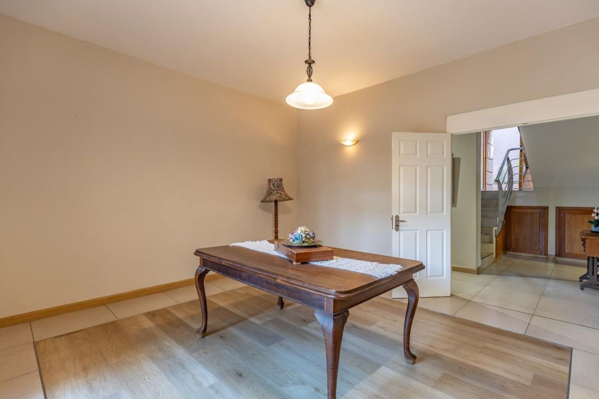 A living area featuring a mix of tiled and wood-look laminate flooring, illuminated by a pendant light and wall sconce.