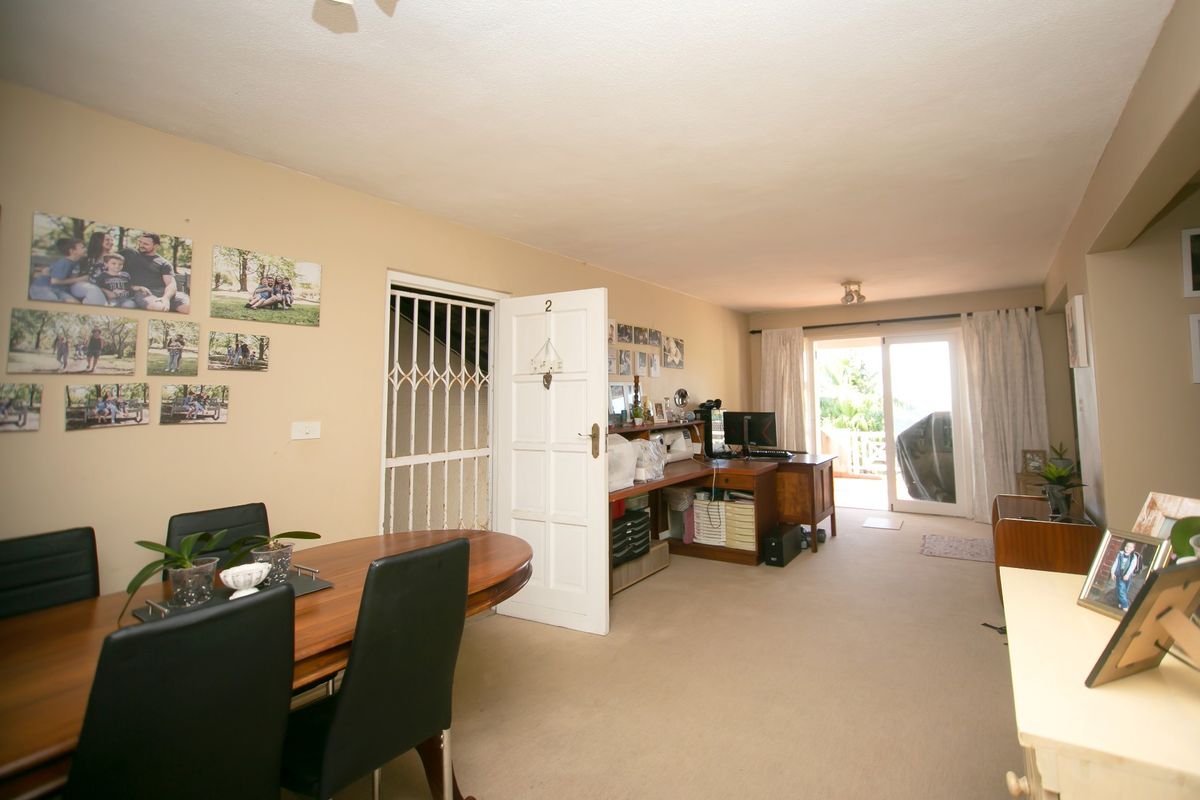 Spacious open-plan living and dining area featuring neutral walls, carpeted flooring, and direct access to an outdoor patio through sliding glass doors.