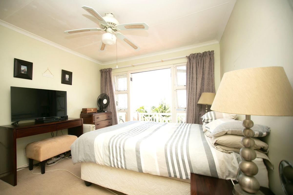 A bedroom featuring a ceiling fan and sliding glass doors that open to an outdoor area, providing natural light and ventilation.