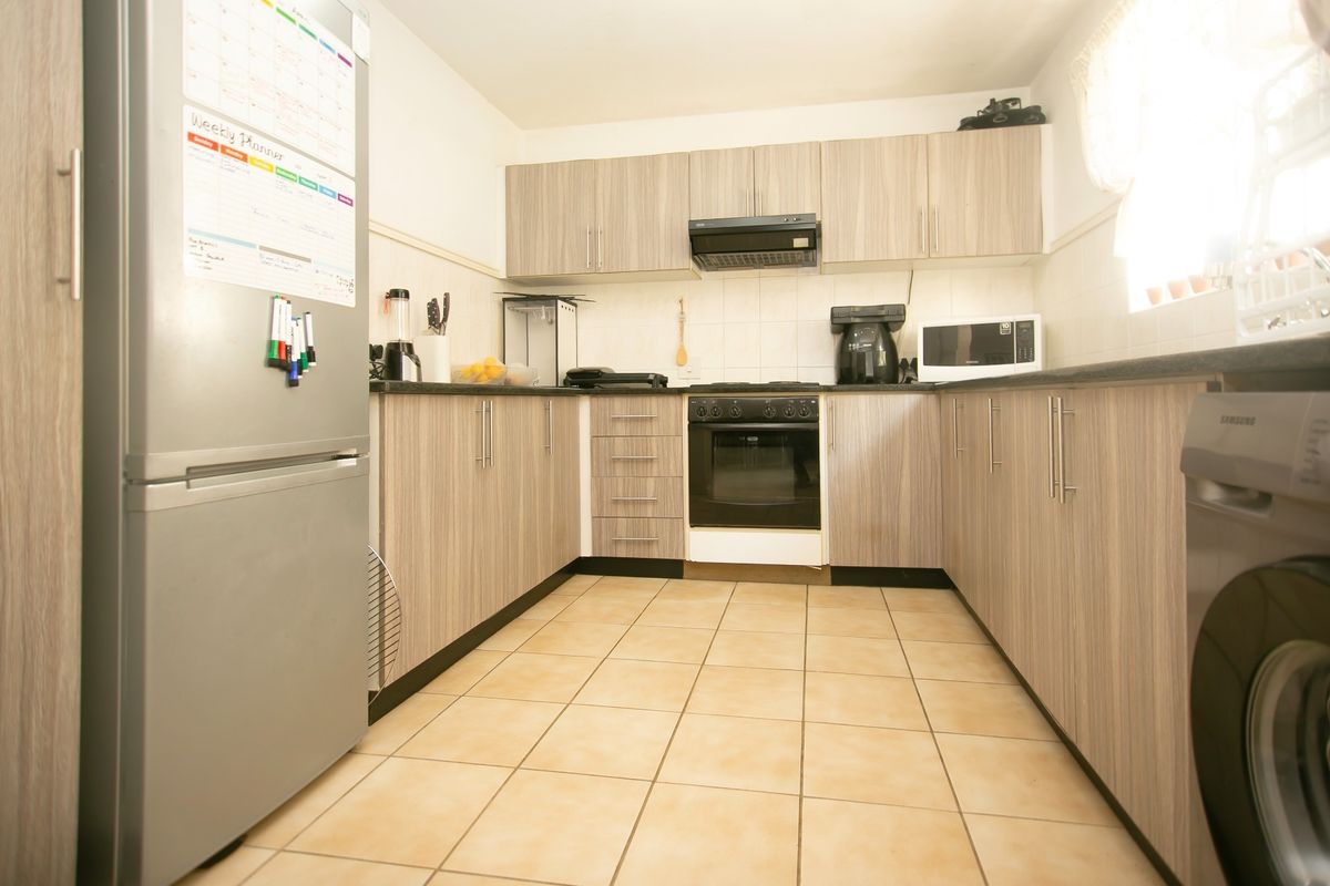 A functional kitchen featuring wood-look laminate cabinetry, tiled flooring, a built-in oven, and an extractor fan, providing a practical workspace.