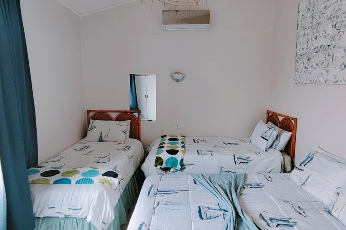 A bedroom featuring tiled flooring, a vaulted ceiling, and a wall-mounted split-system air conditioner.
