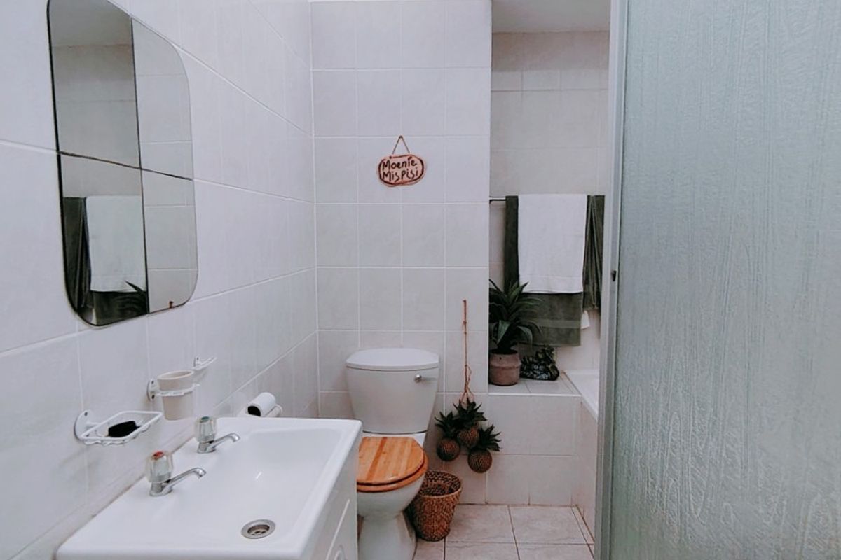 A functional bathroom featuring a vanity basin, toilet, and a shower enclosure with tiled finishes throughout.