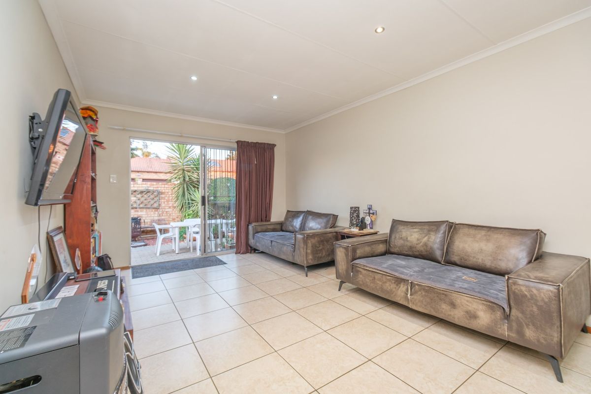 A bright living room featuring tiled flooring, recessed downlighting, and a sliding glass door providing direct access to the outdoor patio area.