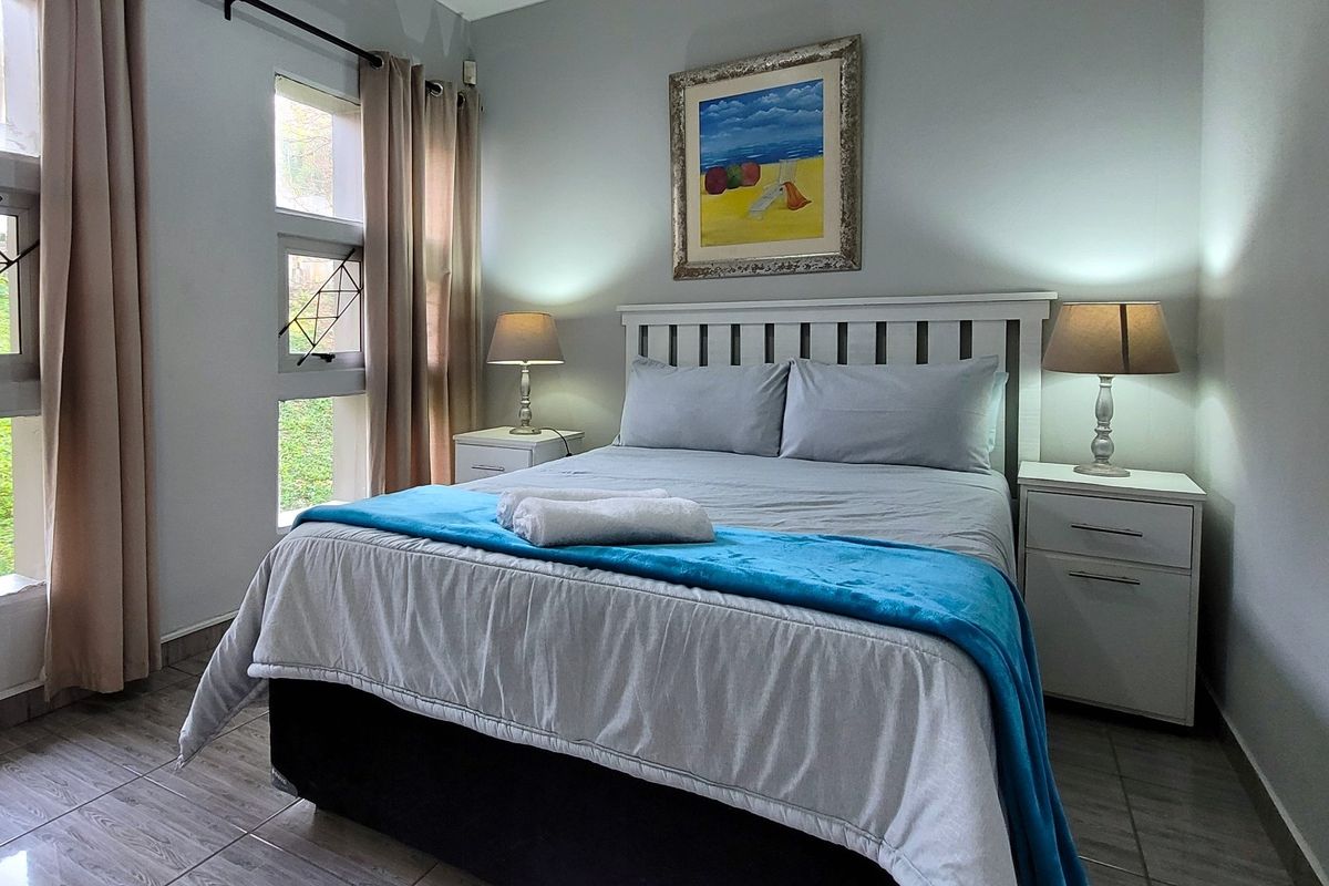 A well-maintained bedroom featuring tiled flooring and large casement windows that provide natural light and garden views.