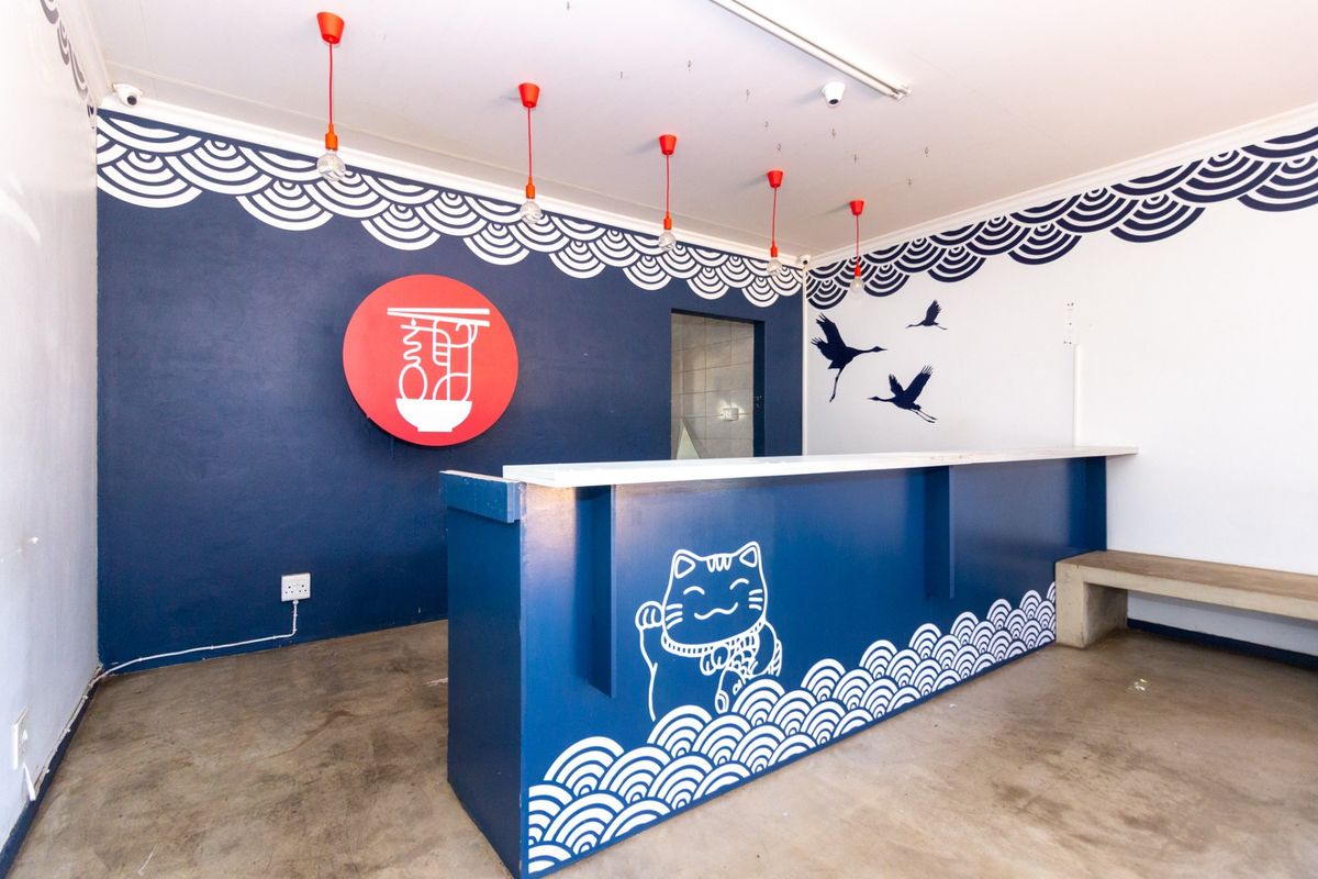 A clean retail service area featuring a custom-painted built-in counter, polished concrete floors, and decorative pendant lighting.