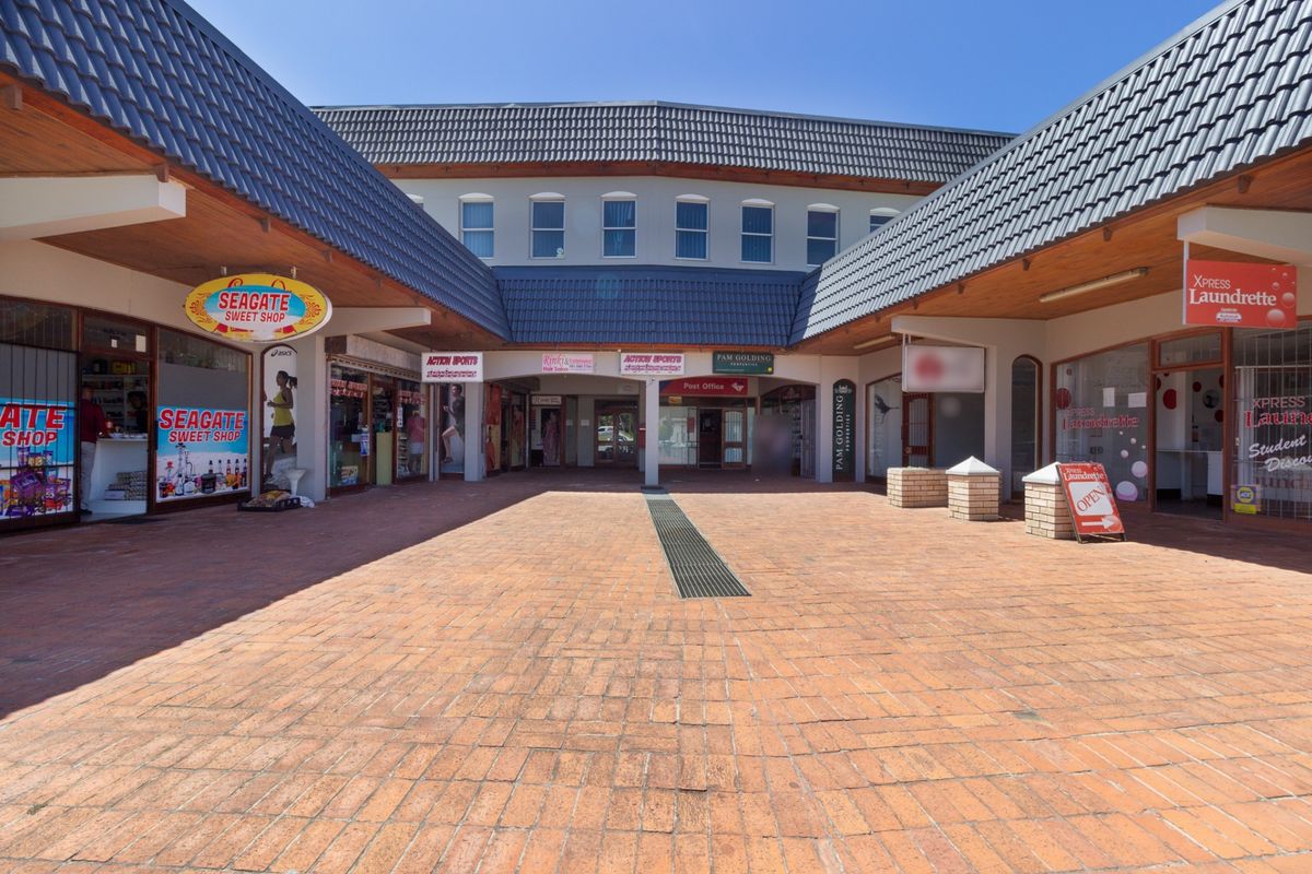 A central paved courtyard area within a retail complex, featuring covered walkways and multiple shopfront entrances under a tiled roof structure.