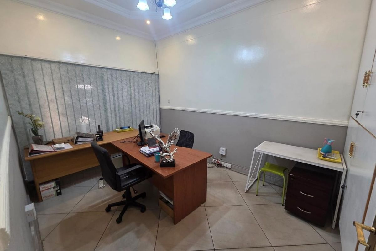A functional office space featuring tiled flooring, vertical blinds, and crown molding, providing a practical environment for professional work.