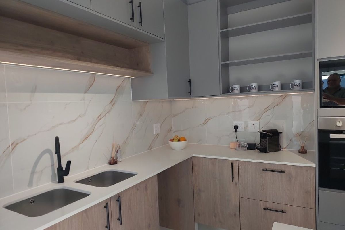 Modern kitchen featuring wood-grain and grey cabinetry, stone countertops, marble-look splashback, integrated oven, and high-quality finishes with under-cabinet lighting.