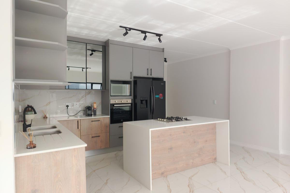 Modern kitchen featuring a central island with gas cooktop, built-in oven and microwave, marble-look splashback, and high-quality porcelain floor tiles.