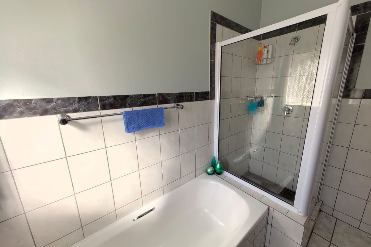 A functional bathroom featuring a built-in bathtub and a separate shower enclosure with tiled walls and a decorative border.