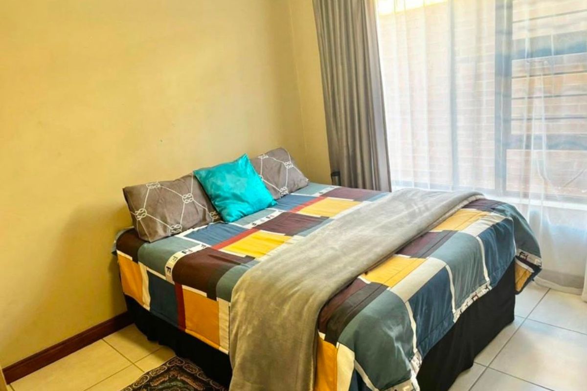 A functional bedroom featuring tiled flooring and large windows with curtain tracks, providing natural light and a neutral base for interior design.