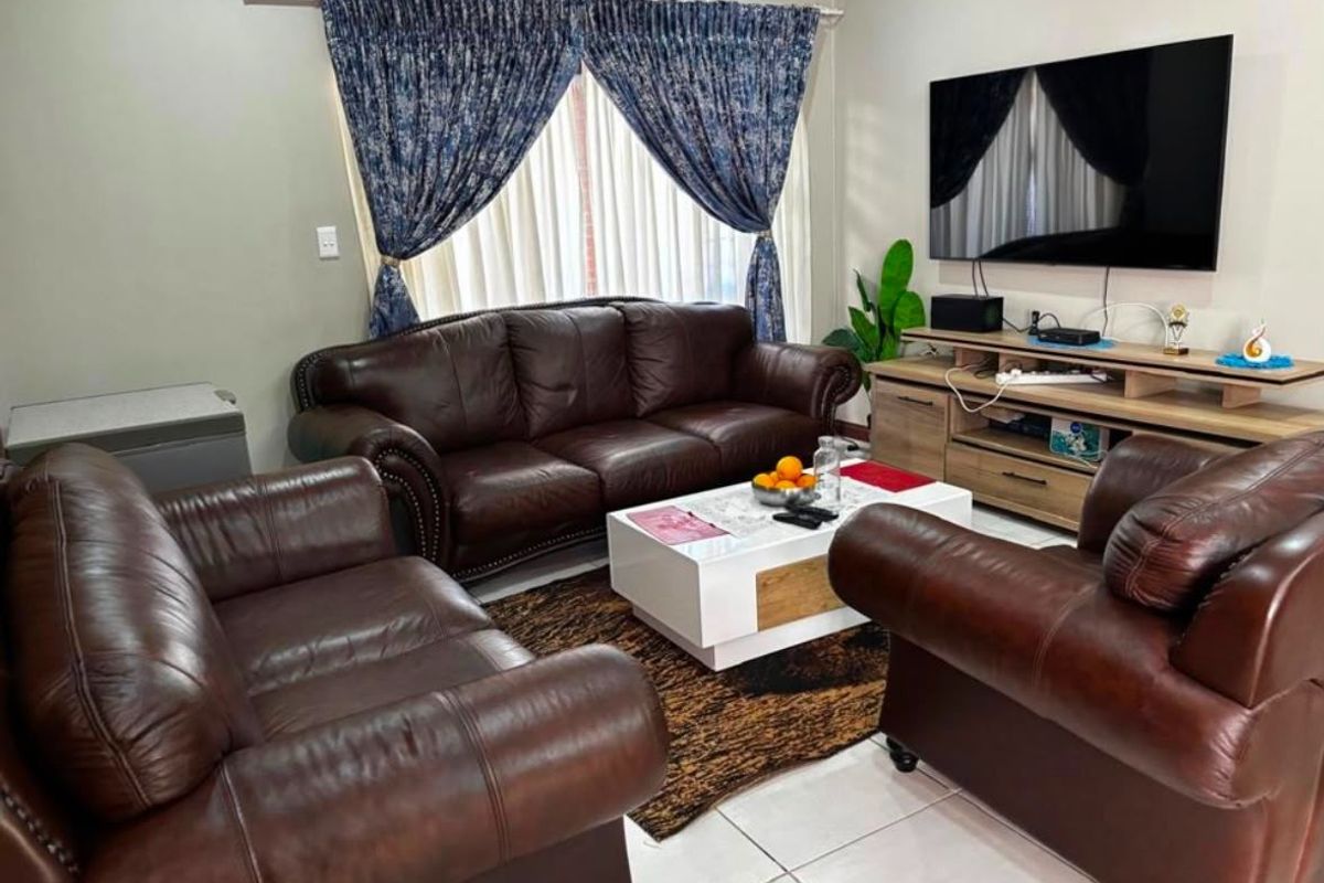 A comfortable living room featuring tiled flooring and a wall-mounted air conditioning unit, providing a functional and climate-controlled space.