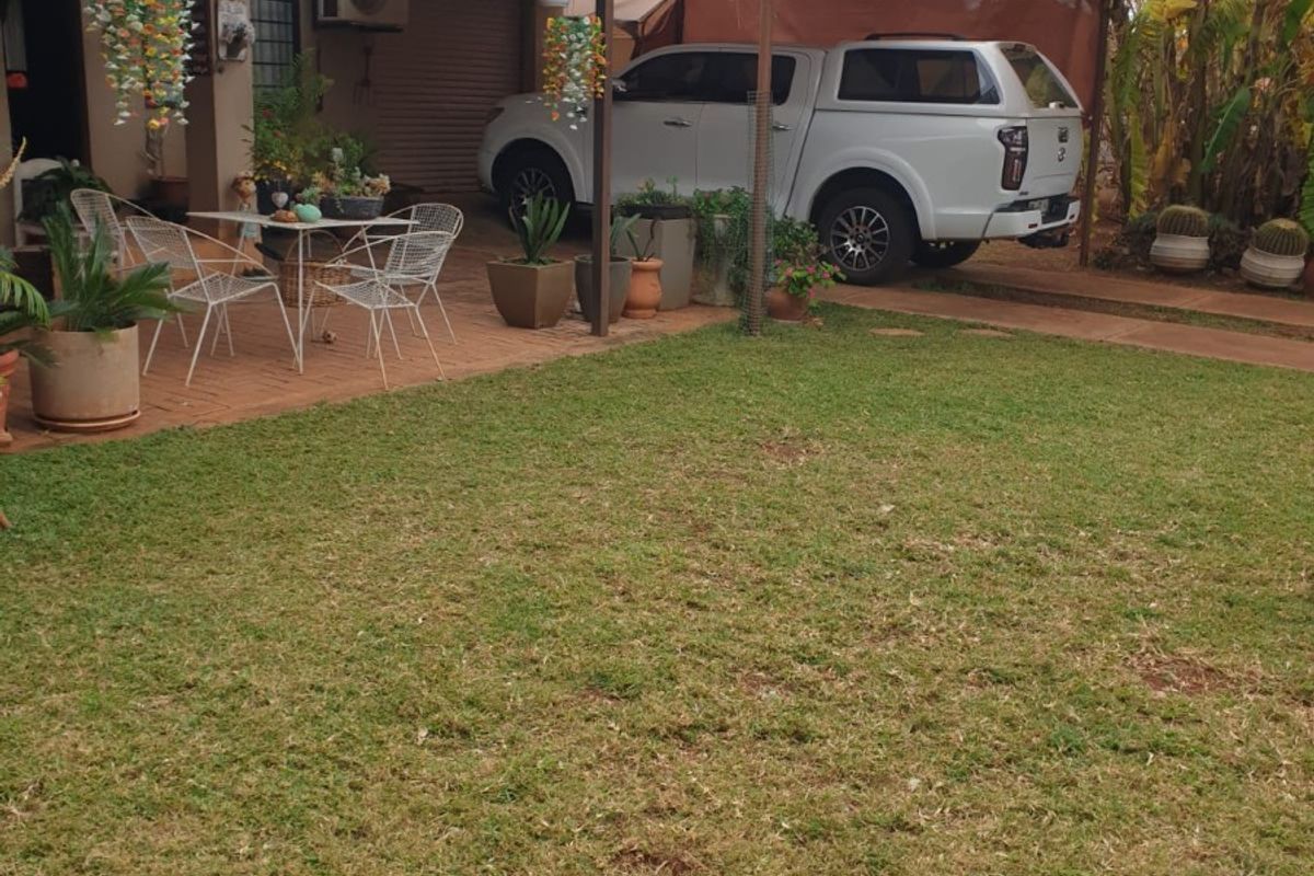 Rear exterior view featuring a paved patio area with shade sails, established lawn, and direct access to the home.