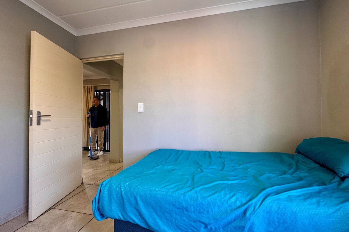 A bedroom featuring tiled flooring and neutral wall finishes, with an internal door leading to an adjacent living space.