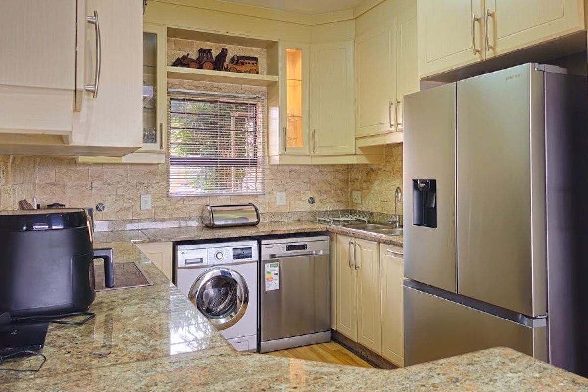 A functional kitchen featuring granite countertops, stone tile backsplash, and integrated appliances including a dishwasher and washing machine.