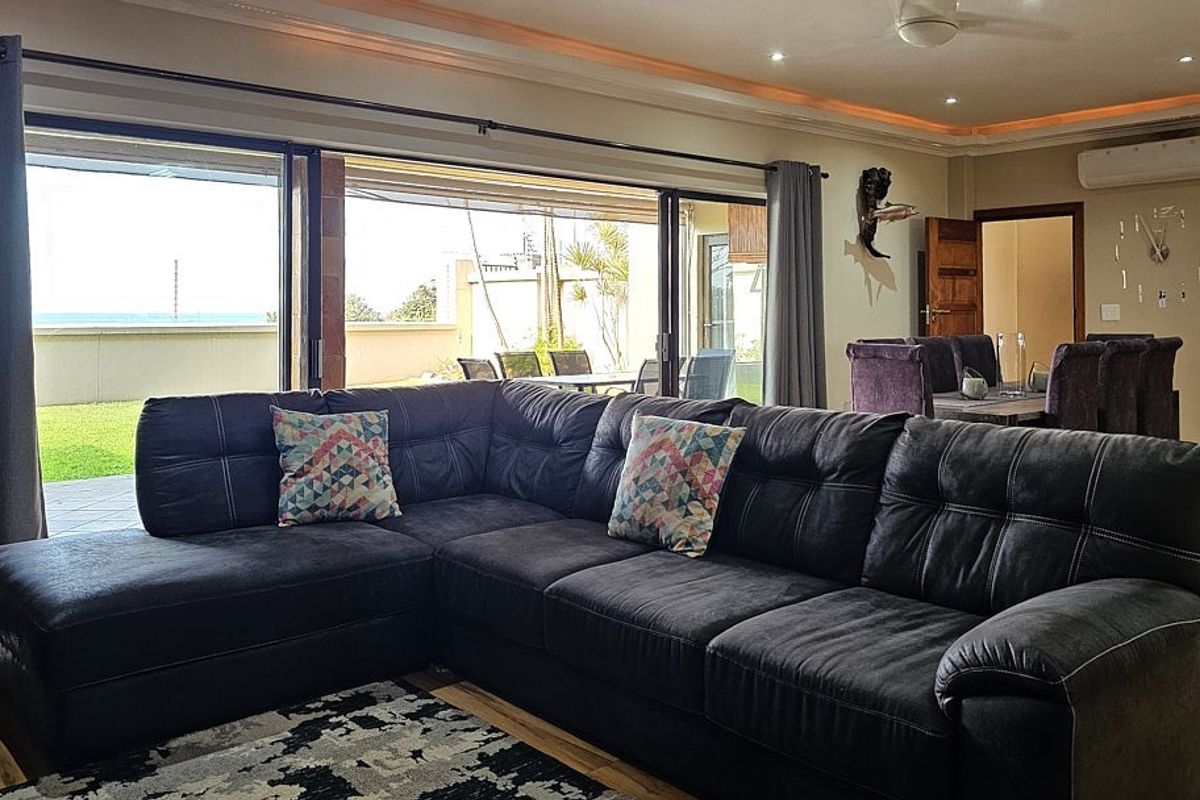 Spacious living room featuring large sliding glass doors that open to an outdoor patio, complemented by modern recessed lighting and air conditioning.