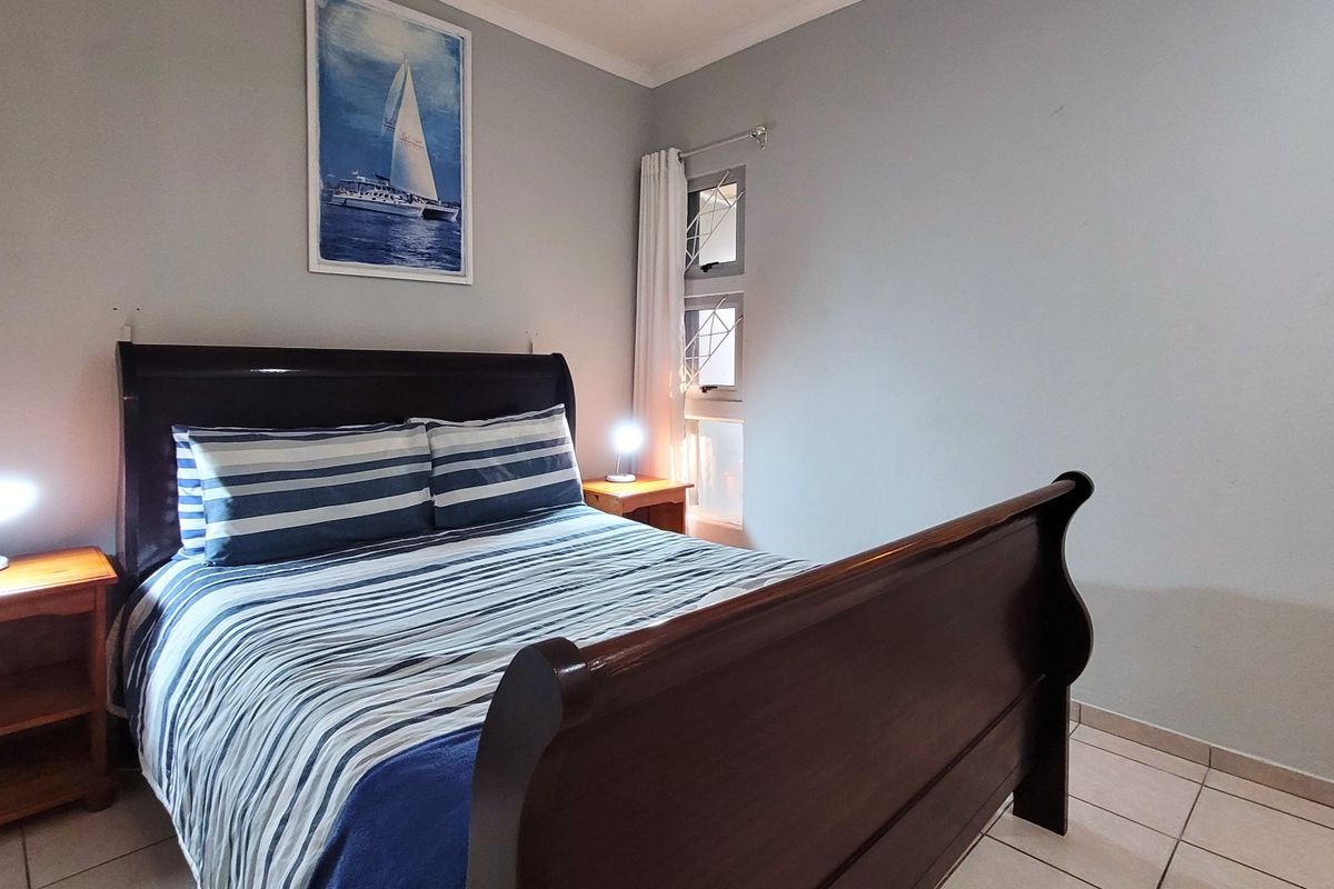 A bedroom featuring tiled flooring and a window fitted with security bars.
