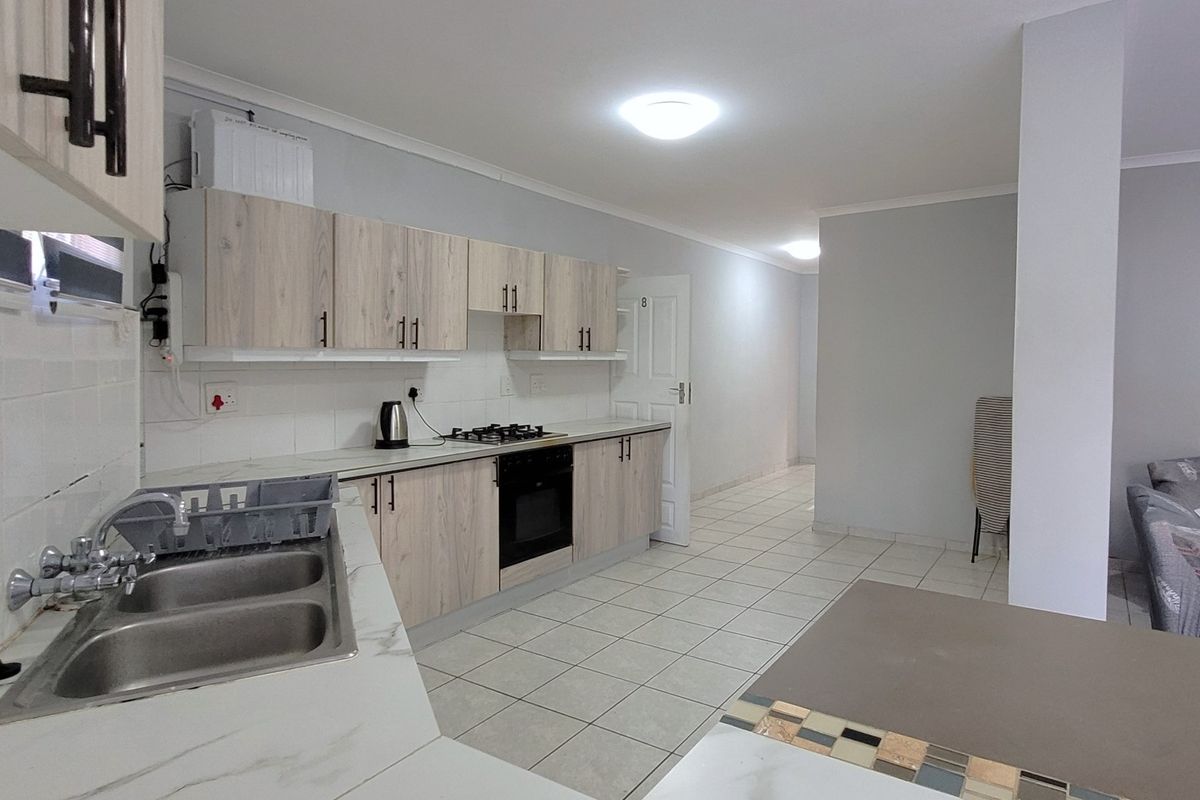 Open plan kitchen featuring light wood-look cabinetry, gas hob, built-in oven, and double bowl sink, flowing into the adjacent living area.