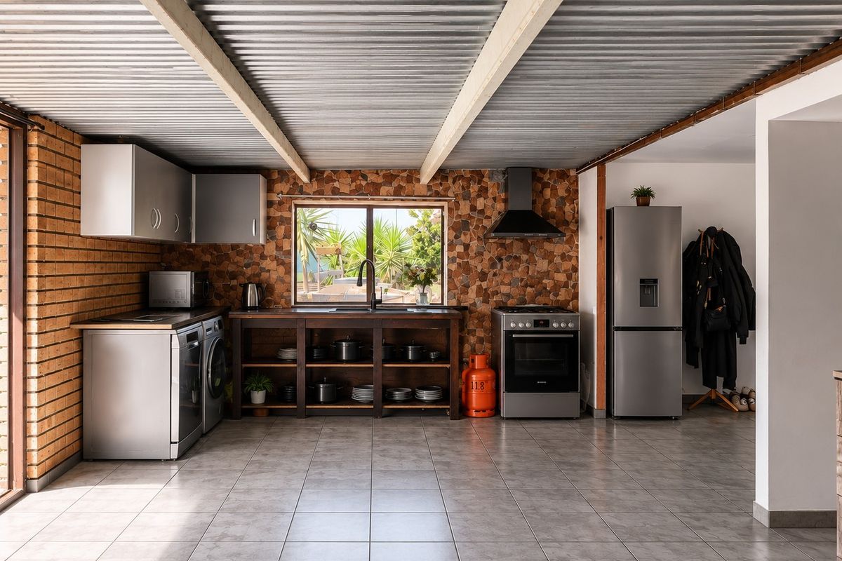 A rustic-style kitchen featuring exposed brick walls, stone mosaic detailing, corrugated metal ceiling, and integrated cabinetry with a freestanding oven and extractor fan.