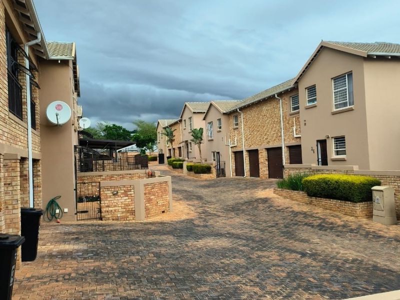 A view of the residential complex driveway featuring paved surfaces, brick exterior walls, and multiple garage access points.