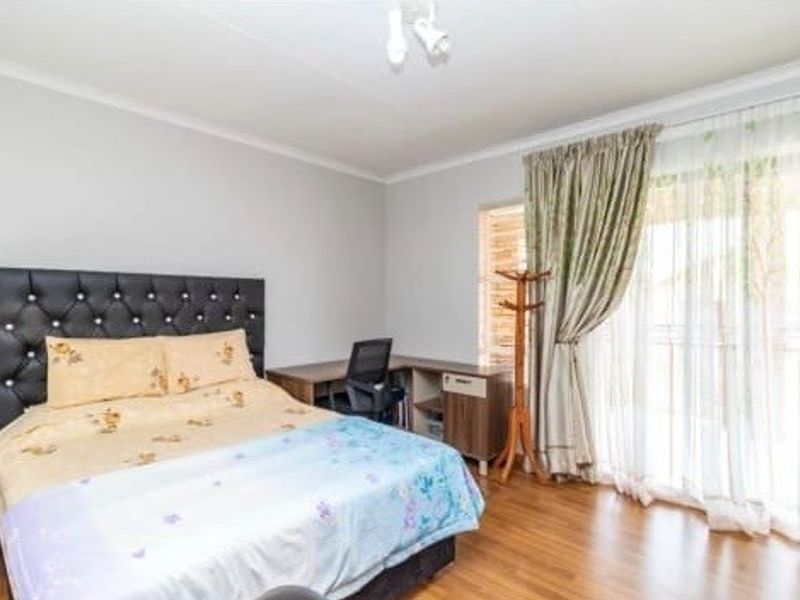 A well-lit bedroom featuring laminate flooring and a sliding glass door that provides access to the exterior.