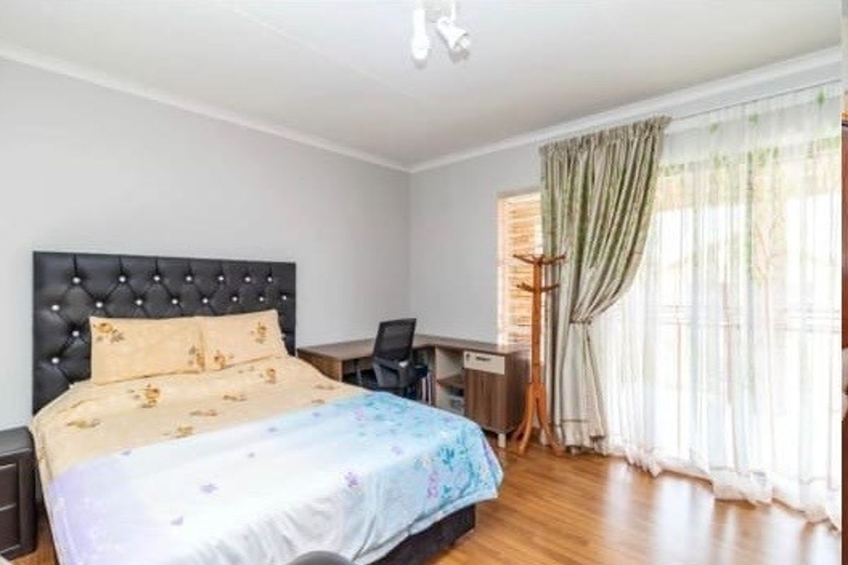 A well-lit bedroom featuring laminate flooring and a sliding glass door that provides access to the exterior.