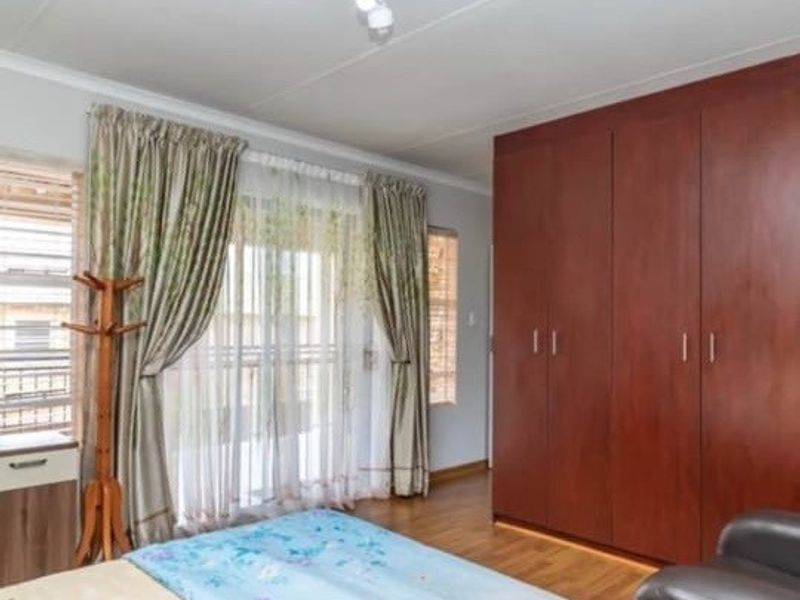 A bedroom featuring laminate flooring, a large built-in wooden wardrobe, and a sliding glass door providing access to an outdoor area.