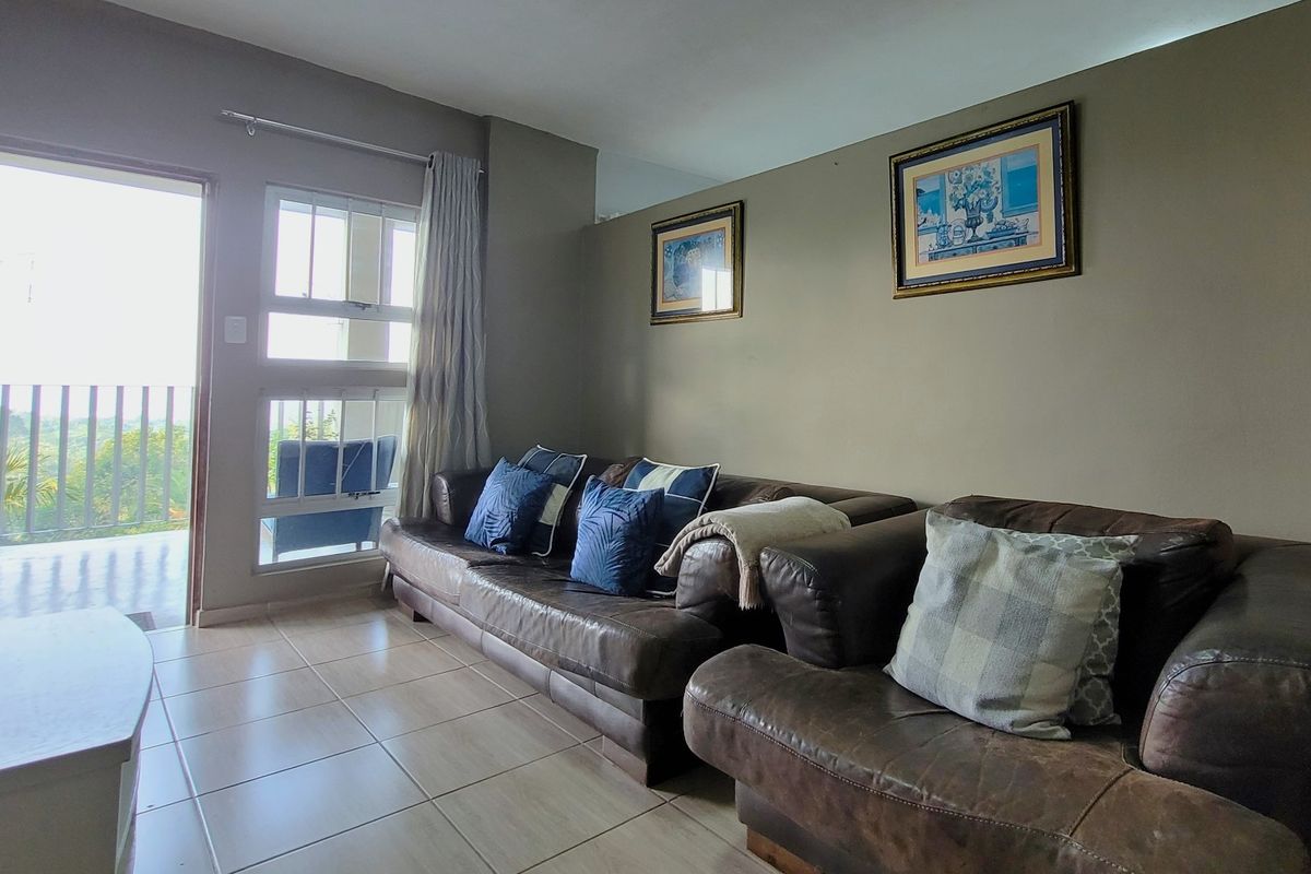 A living room featuring tiled flooring and direct access to an outdoor balcony through a sliding glass door.