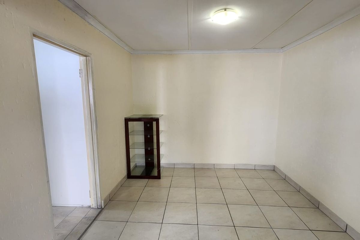 A vacant living area featuring neutral tiled flooring and simple ceiling finishes, offering a blank canvas for interior design updates.