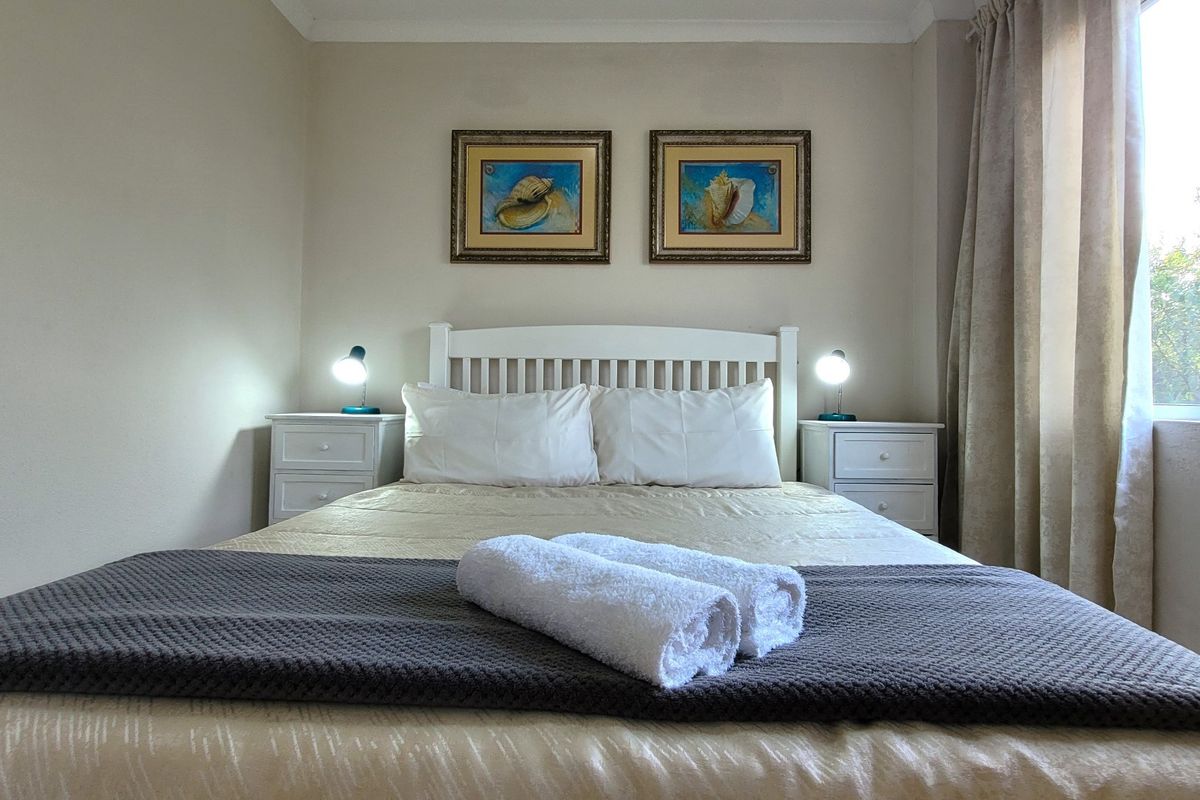 A well-maintained bedroom featuring neutral wall tones, natural light from the window, and a clean, functional layout.