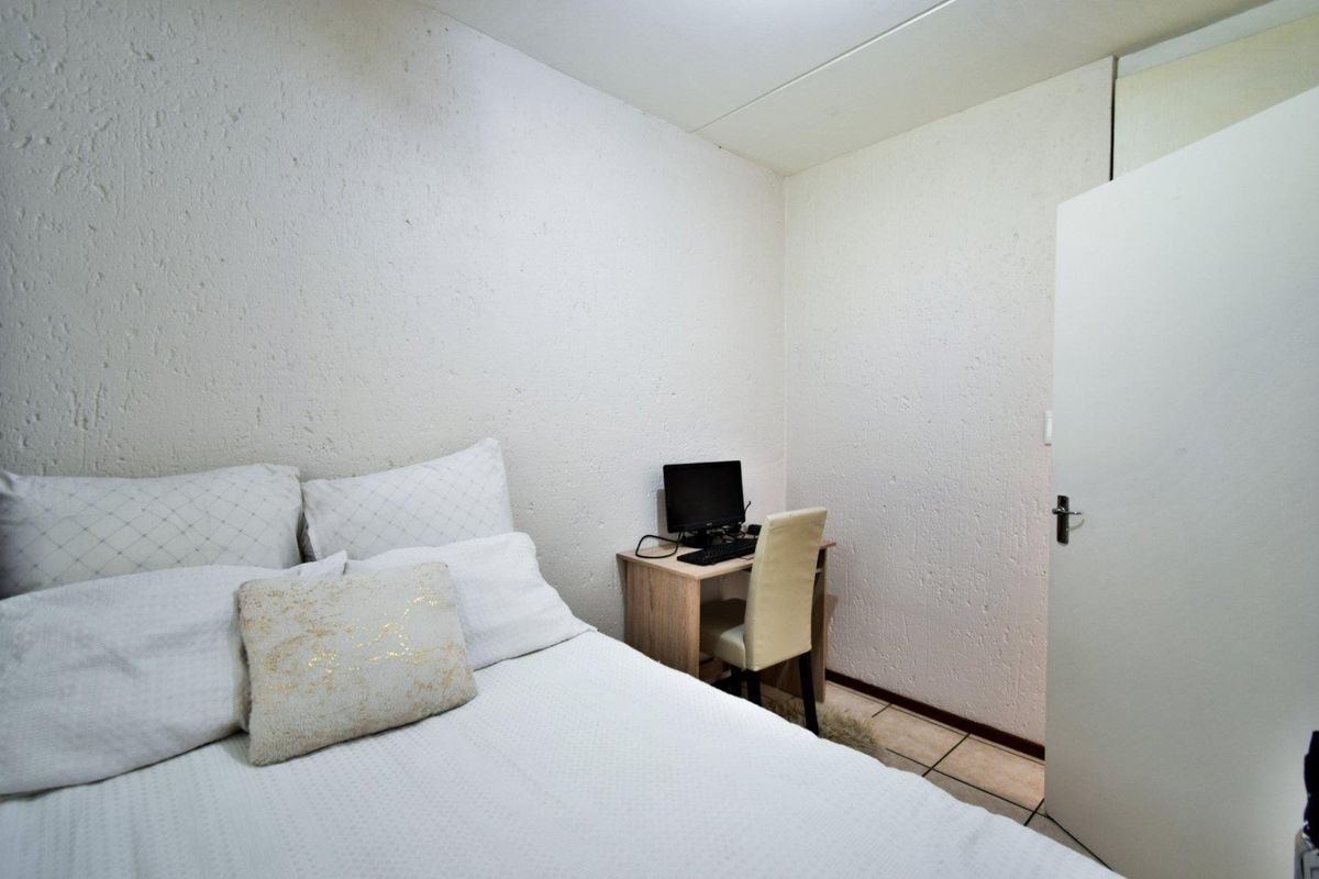 A compact bedroom featuring tiled flooring and textured wall finishes, providing a functional space for rest or study.