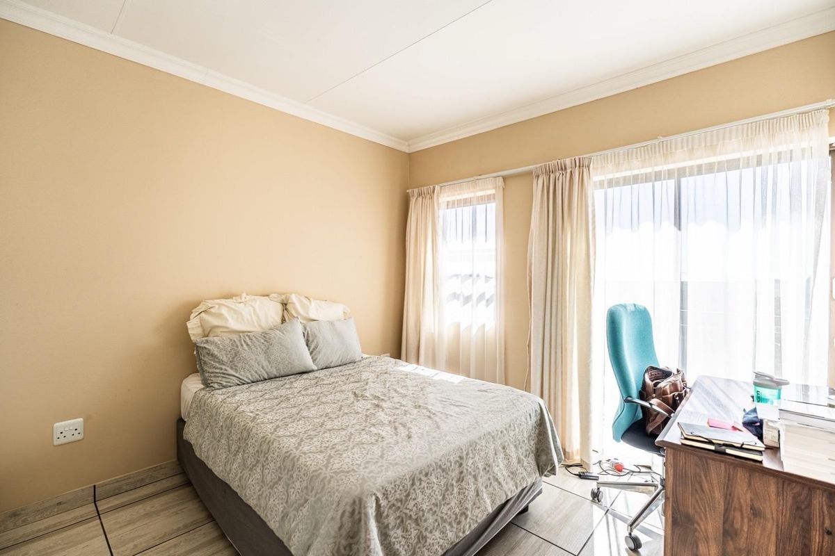 A bedroom featuring tiled flooring, coved ceilings, and a sliding glass door providing access to an outdoor area.