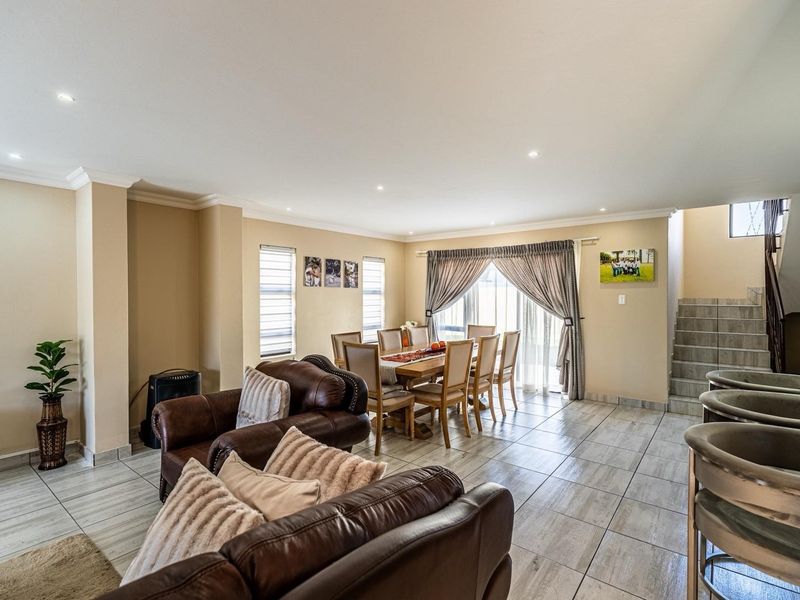 Spacious open-plan living and dining area featuring tiled flooring, recessed lighting, and direct access to the outdoors via sliding glass doors.