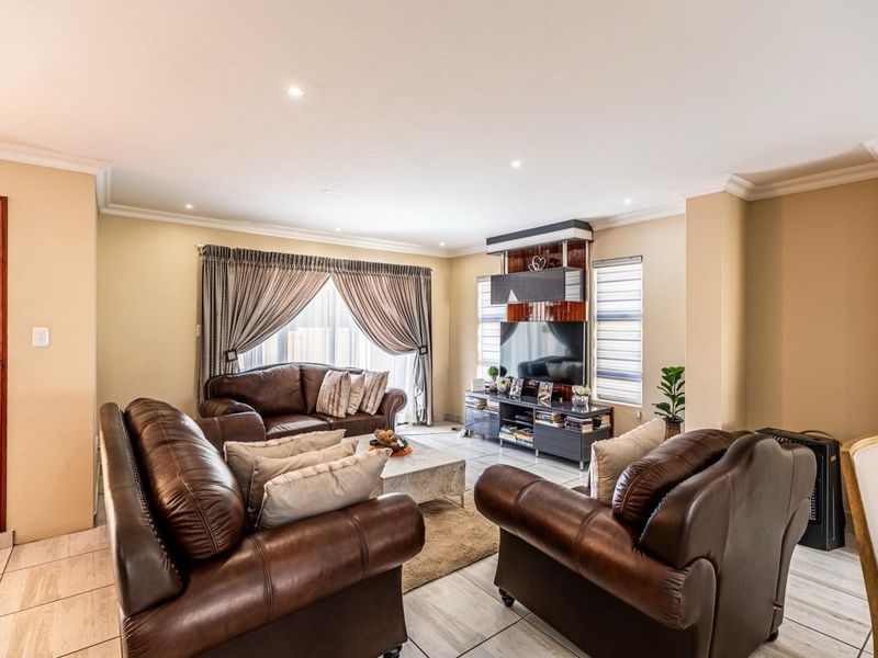 A well-maintained living room featuring tiled flooring, recessed downlighting, decorative cornice, and a custom built-in media unit.