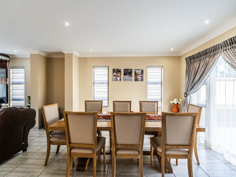 A well-lit dining area featuring neutral wall tones, ceramic tiled flooring, recessed lighting, and direct access to the outdoors via a sliding glass door.