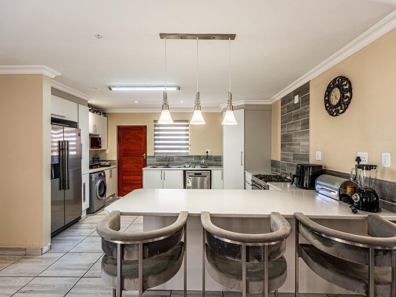 Modern kitchen featuring a central island with breakfast bar, stone countertops, tiled backsplash, and integrated cabinetry with quality finishes.