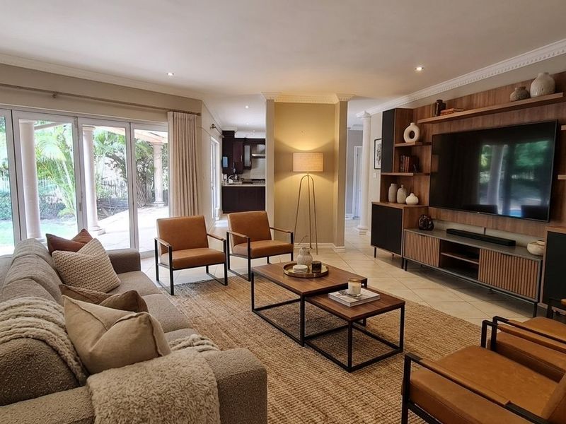 Spacious living room featuring built-in media cabinetry, tiled flooring, and large sliding glass doors providing seamless access to the outdoor patio area.