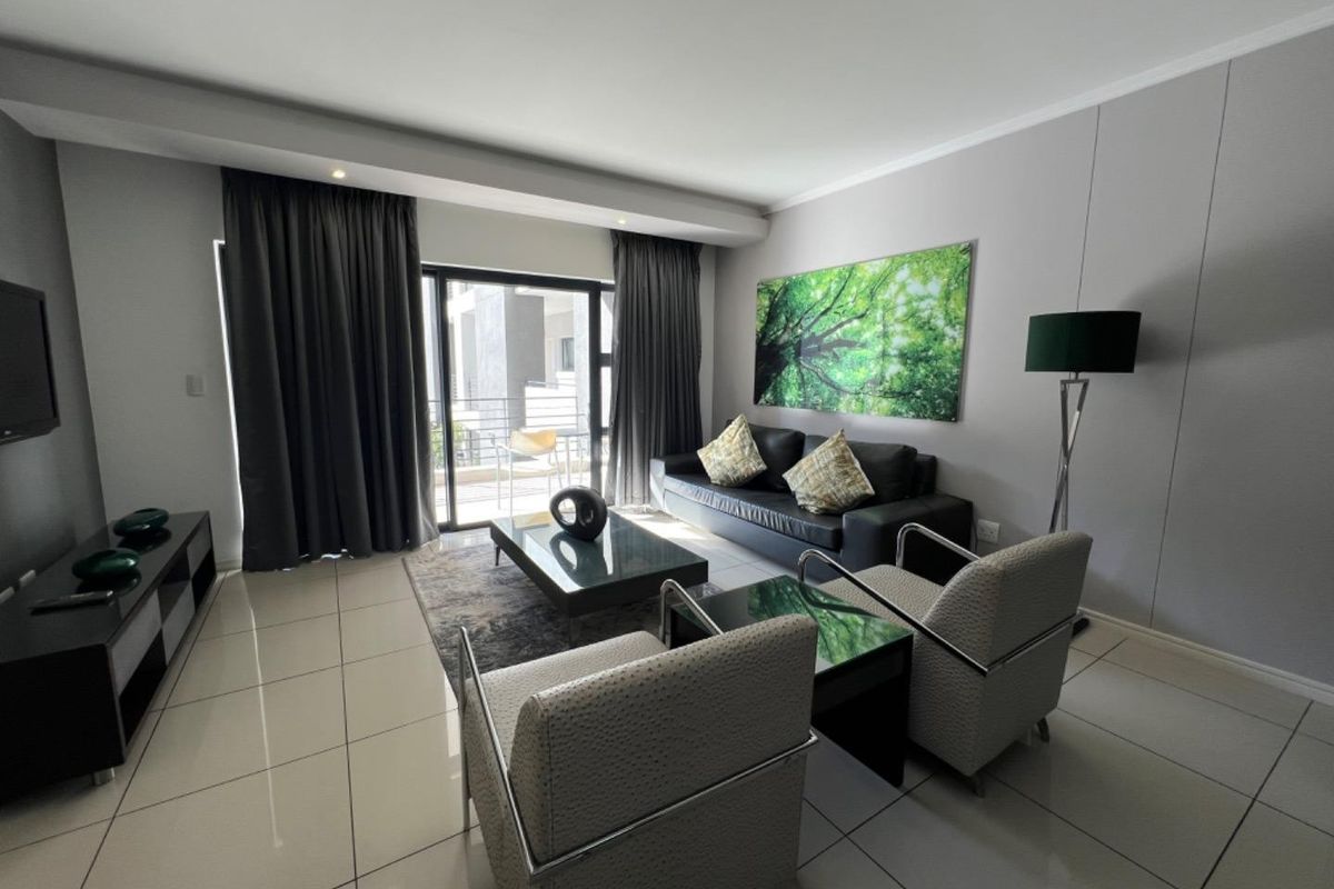 A modern, well-maintained living room featuring large format floor tiles, recessed lighting, and a sliding glass door providing access to an outdoor balcony.