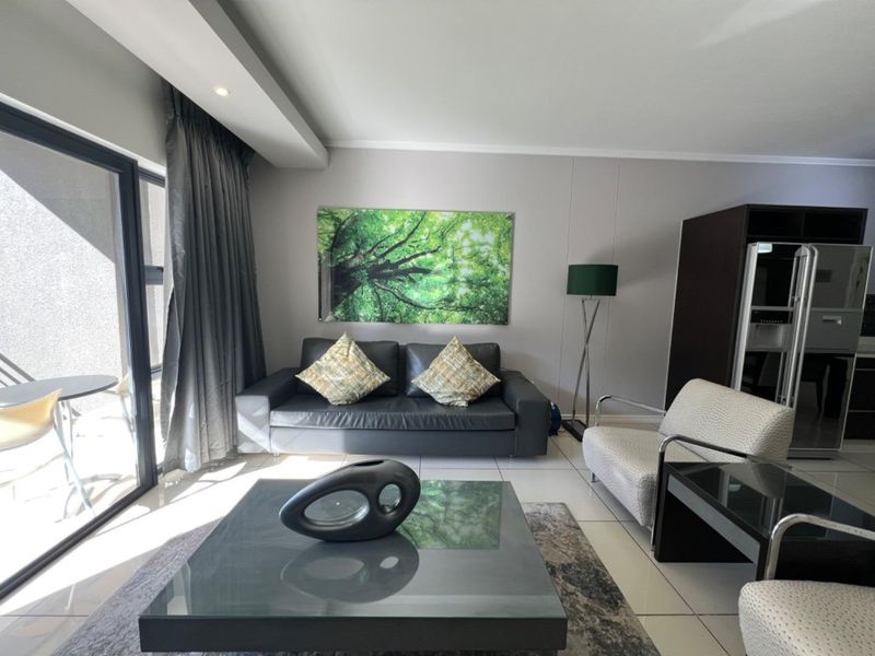 A bright and modern living room featuring tiled flooring, recessed ceiling lighting, and large sliding glass doors providing access to the balcony.