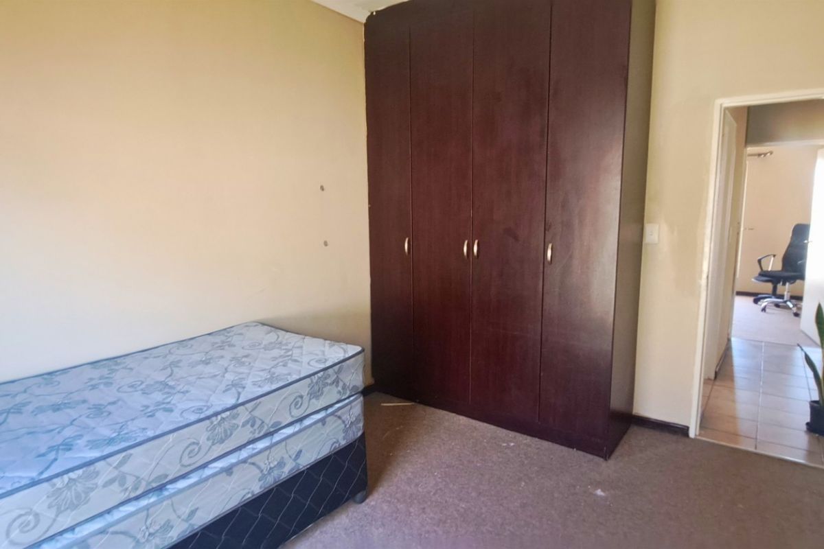 A bedroom featuring a dark wood built-in wardrobe, carpeted flooring, and neutral wall finishes.